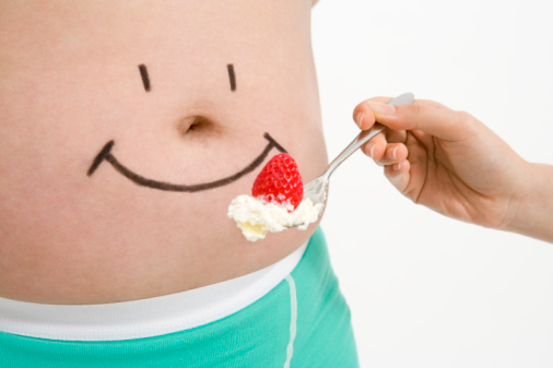 woman-trying-to-feed-a-drawing-of-smiley-face-on-stomach-picture-id95502397