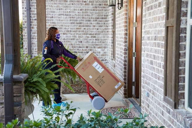 A FedEx Freight Direct employee transports a large package into a customer's home.